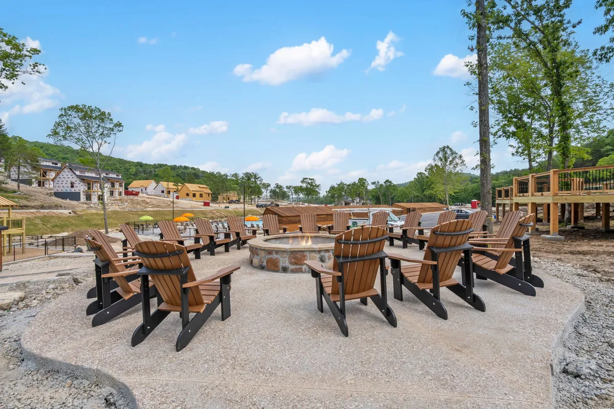 A cozy outdoor fire pit surrounded by Adirondack chairs and a scenic landscape, inviting guests to gather, relax, and enjoy the evening together under the stars.